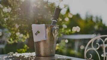 Un balde de metal con una botella y una servilleta sobre una mesa al aire libre.