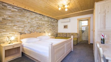 A wooden-paneled bedroom with a stone wall, a double bed, bedside tables, and a wooden bench.
