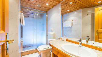 A modern bathroom with a wooden ceiling, a glass shower enclosure, a white toilet, and a large mirror above a sink.