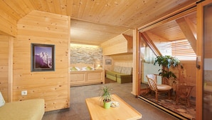 A cozy wooden interior with a sofa, a small table with a plant, and a view through a glass door. - Penzion Berc (Bled)