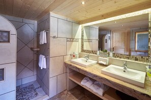 A modern bathroom with two sinks, a large mirror, and a shower area.