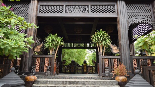 A traditional wooden gate with intricate carvings and a stone staircase leading up to it. - Bagan Central Hotel (Nyaung-U)