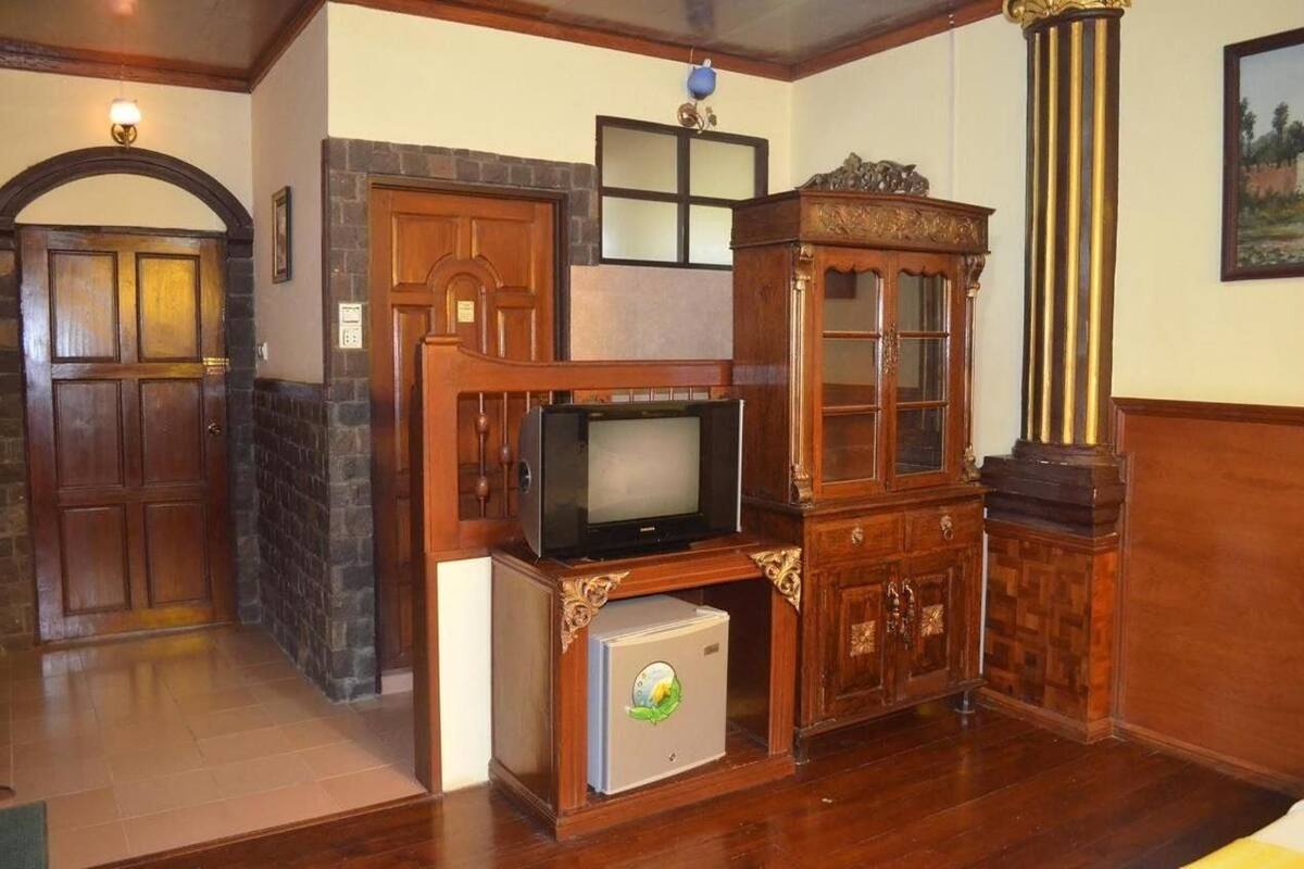 A room with a wooden cabinet, a television, and a small refrigerator.
