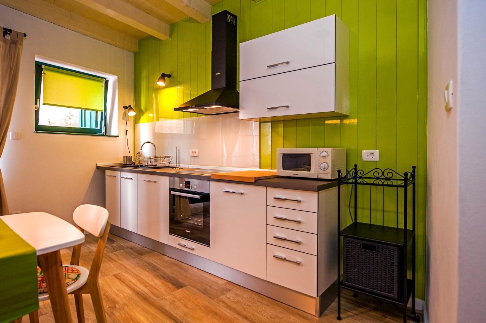 A compact kitchen with a microwave, oven, and a sink.