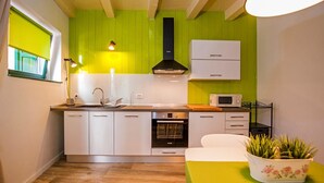 A compact kitchen with a green accent wall, white cabinets, a microwave, and a small oven. - Apartment Luxury Rovinj (Rovinj)