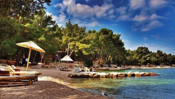 A beach with clear water, lounge chairs, umbrellas, and a rocky shoreline. - Apartment Luxury Rovinj (Rovinj)