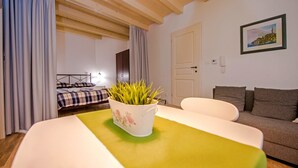 A cozy room with a bed, a sofa, a table with a plant, and a door. - Apartment Luxury Rovinj (Rovinj)