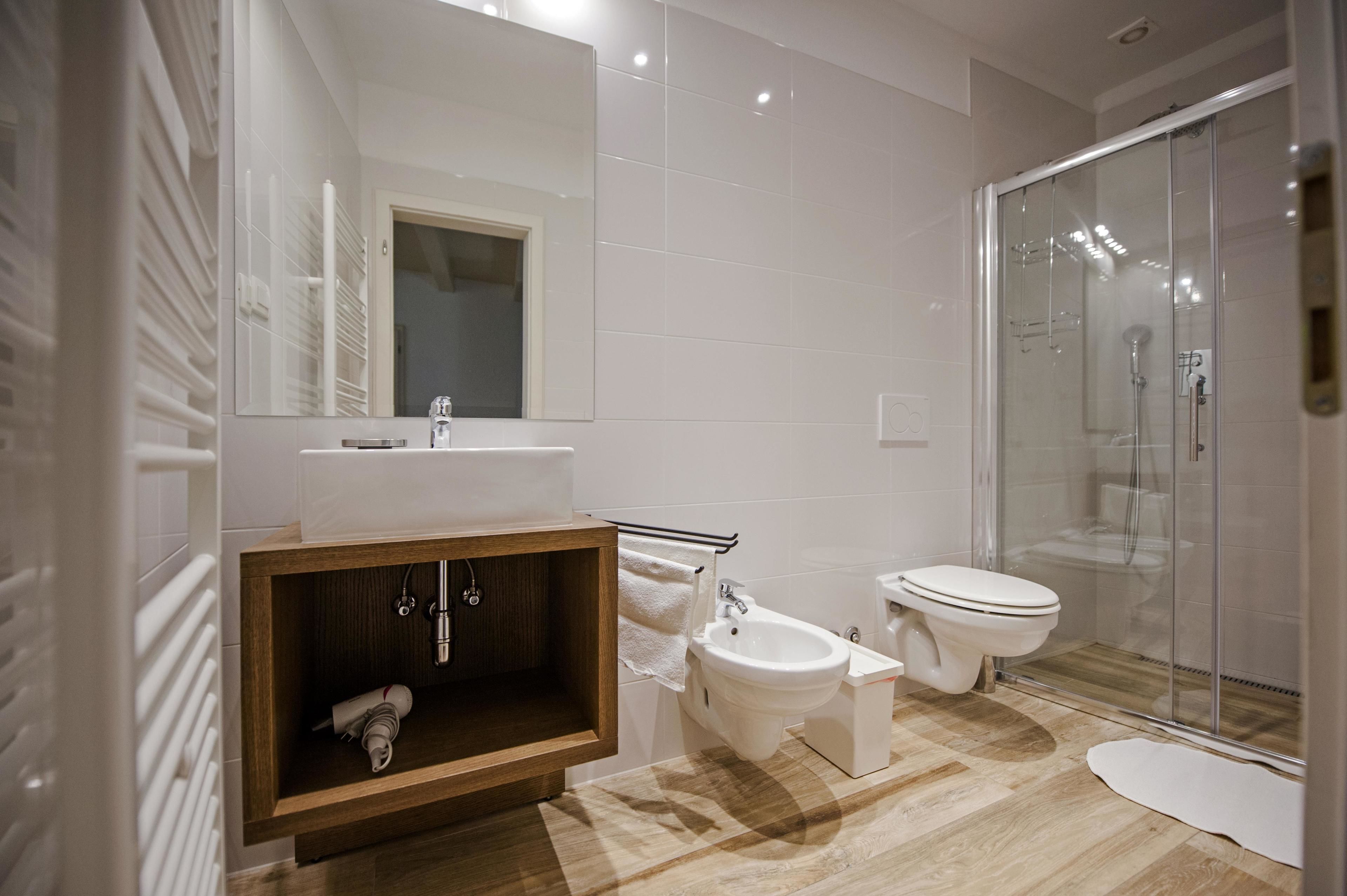A modern bathroom with a glass-enclosed shower, a wooden vanity, and a white sink.