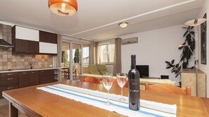 A modern kitchen with a wooden island, two wine glasses, and a bottle of wine. - Apartments Levan Ceja (Medulin)