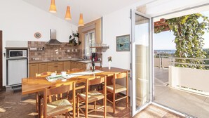 A modern kitchen with wooden furniture, a dining table, and a view of the outdoors. - Apartments Levan Ceja (Medulin)