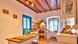 Une cuisine chaleureuse avec une table en bois, des chaises blanches et une porte bleue.