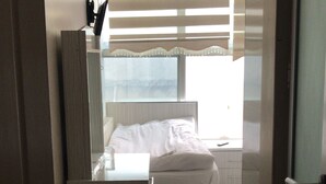 A bedroom with a bed, a desk, and a window with blinds. - Grand Silvan Otel (Silvan)