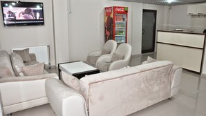 A living room with a sofa, armchairs, a coffee table, a TV, and a Coca-Cola refrigerator. - Grand Silvan Otel (Silvan)