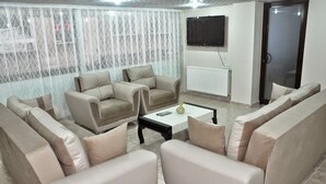 A living room with beige sofas, a coffee table, and a TV mounted on the wall. - Grand Silvan Otel (Silvan)