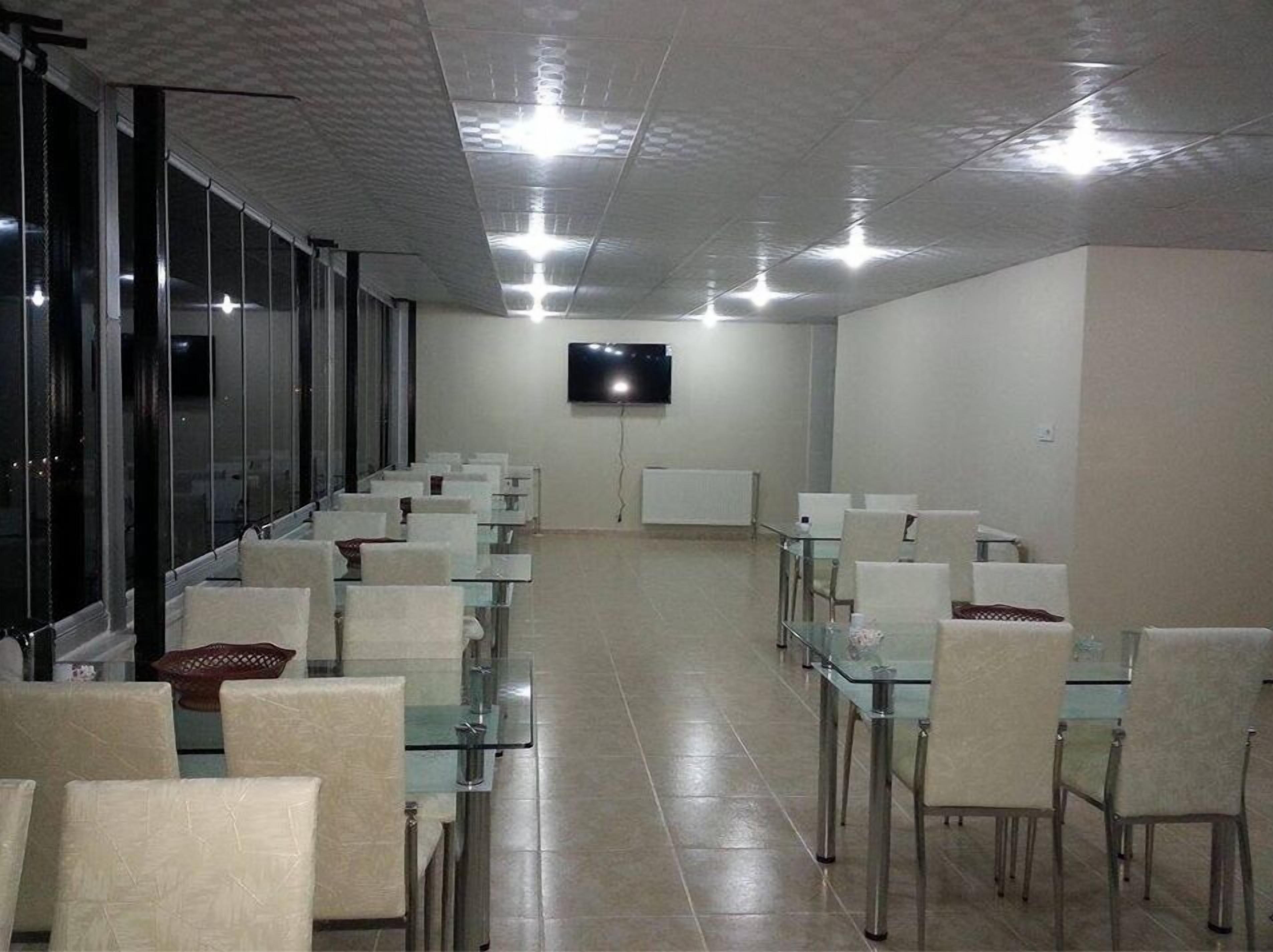 A conference room with glass tables and chairs, a flat-screen TV on the wall, and a long windowed wall.