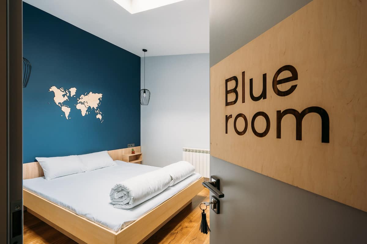 Quarto moderno com uma cama, um mapa-múndi na parede e um letreiro escrito 'Blue room'.