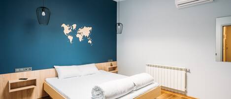 A modern bedroom with a wooden bed, a world map on the wall, and a wooden floor.