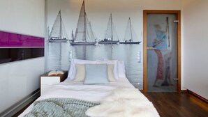 A bedroom with a bed, a nightstand, a wall-mounted TV, and a door with a frosted glass panel. - ELITE APARTMENTS Tre Mare Residence (Gdansk)