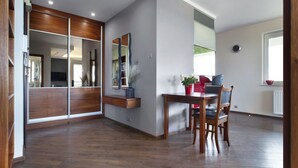A modern interior with a wooden floor, a dining table with chairs, a mirror, and a window with a view. - ELITE APARTMENTS Tre Mare Residence (Gdansk)