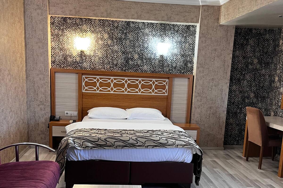 Una habitación de hotel con cama, mesitas de noche, escritorio y silla.