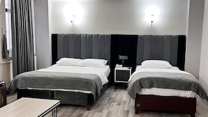 A hotel room with two beds, a small table, and a nightstand with a phone.