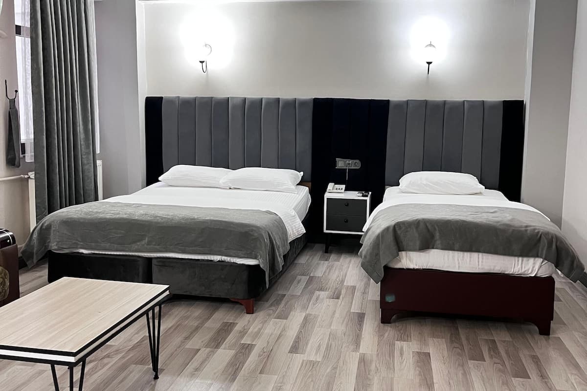 Una habitación de hotel con dos camas, una mesita pequeña y una mesita de noche con un teléfono.