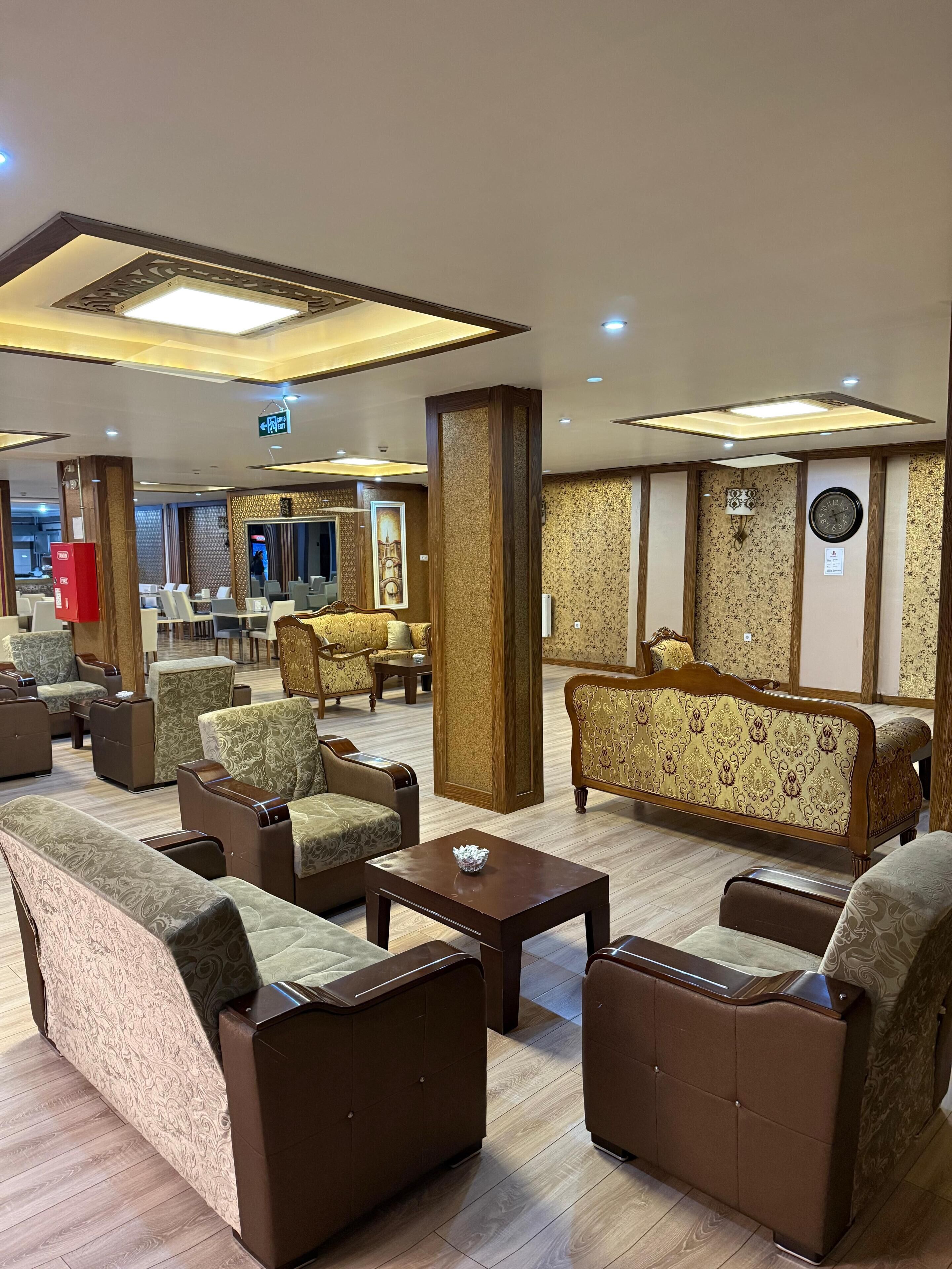 Een hotellobby met banken, fauteuils, een bijzettafeltje en een klok aan de muur.