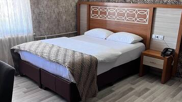 Una habitación de hotel con cama, mesita de noche y aire acondicionado de pared.