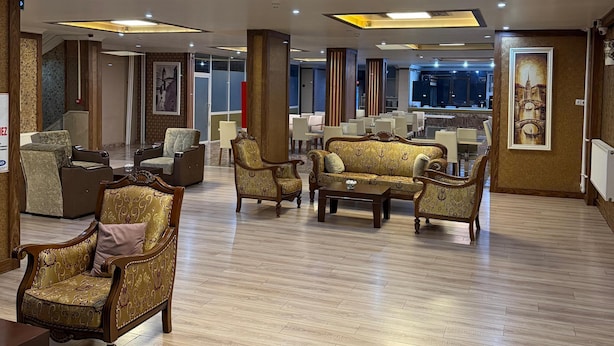A spacious lobby with wooden flooring, ornate sofas, and a modern ceiling design.