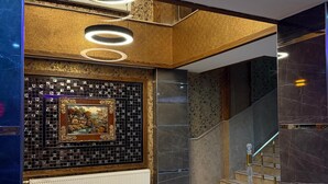 A modern interior with a staircase, a decorative wall with a framed picture, and a patterned floor.
