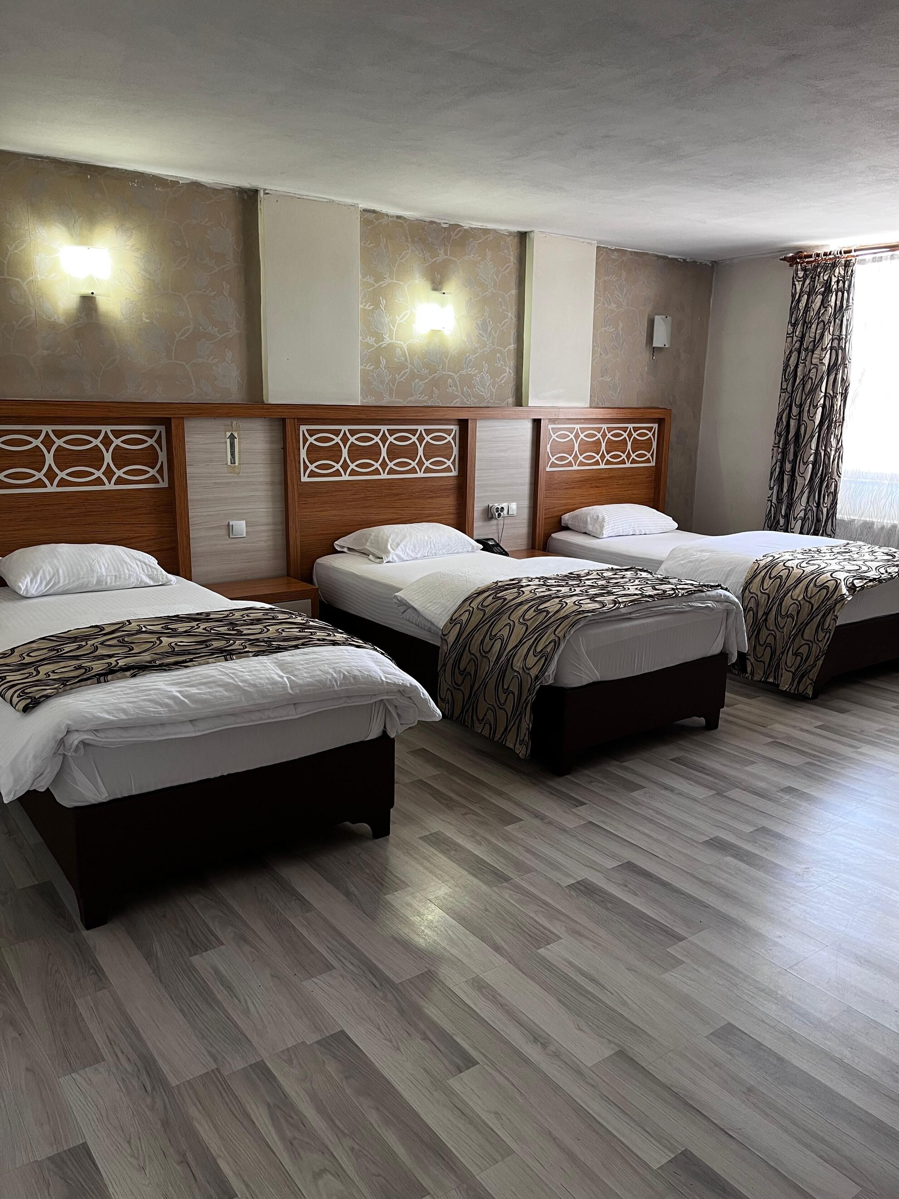 Una habitación de hotel con tres camas, cabeceros de madera y suelo estampado.