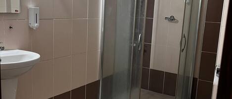 Een badkamer met een douchecabine van glas, een wastafel en een toilet.