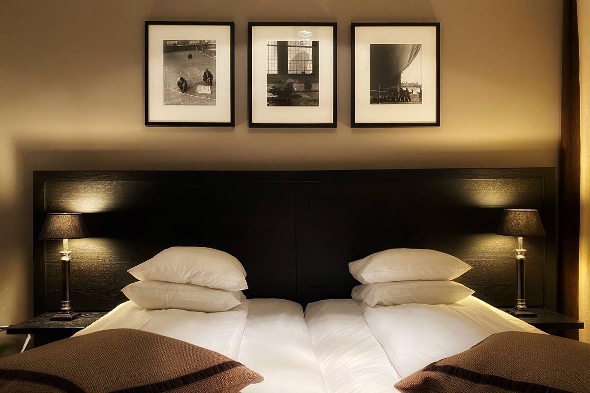 A hotel room with a large bed, two bedside lamps, and three framed photographs on the wall.