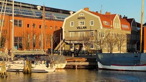 Un hôtel situé au bord de l’eau, appelé « Hôtel Villan », dont le bâtiment principal se distingue par une grande enseigne.