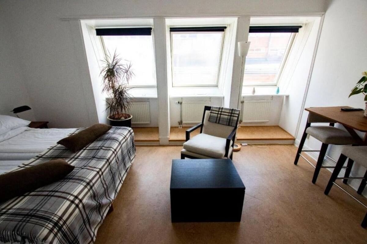 A room with a bed, a chair, a table, and a radiator.