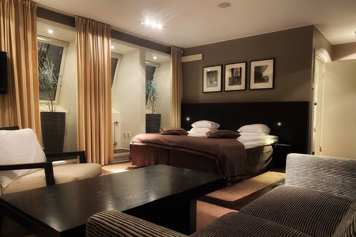 A modern bedroom with a large bed, a desk, and a sofa.