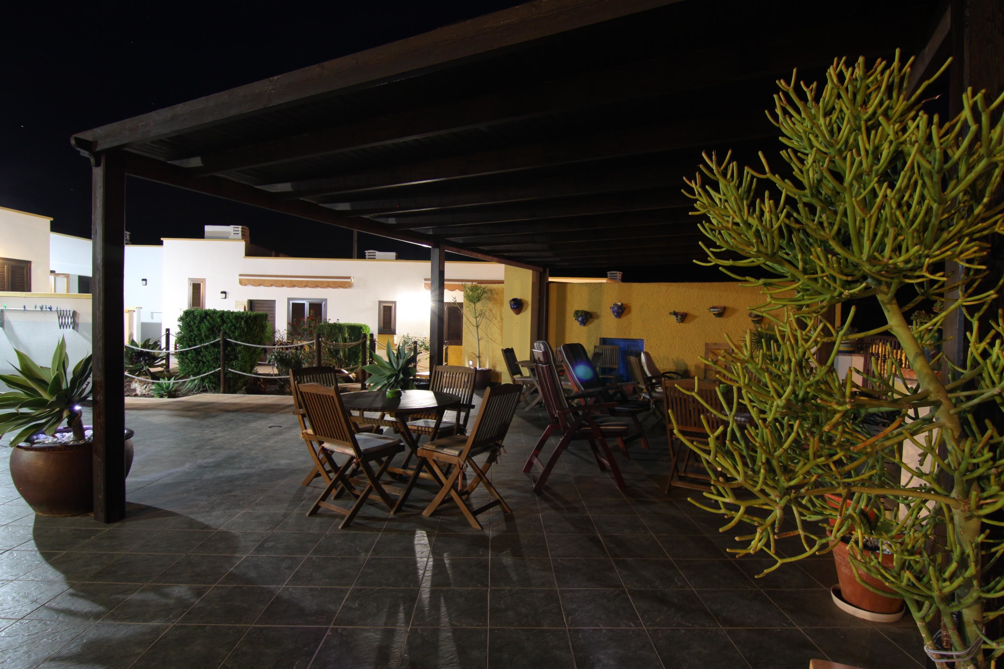 An outdoor patio area with a covered seating arrangement, potted plants, and a view of the surrounding buildings.