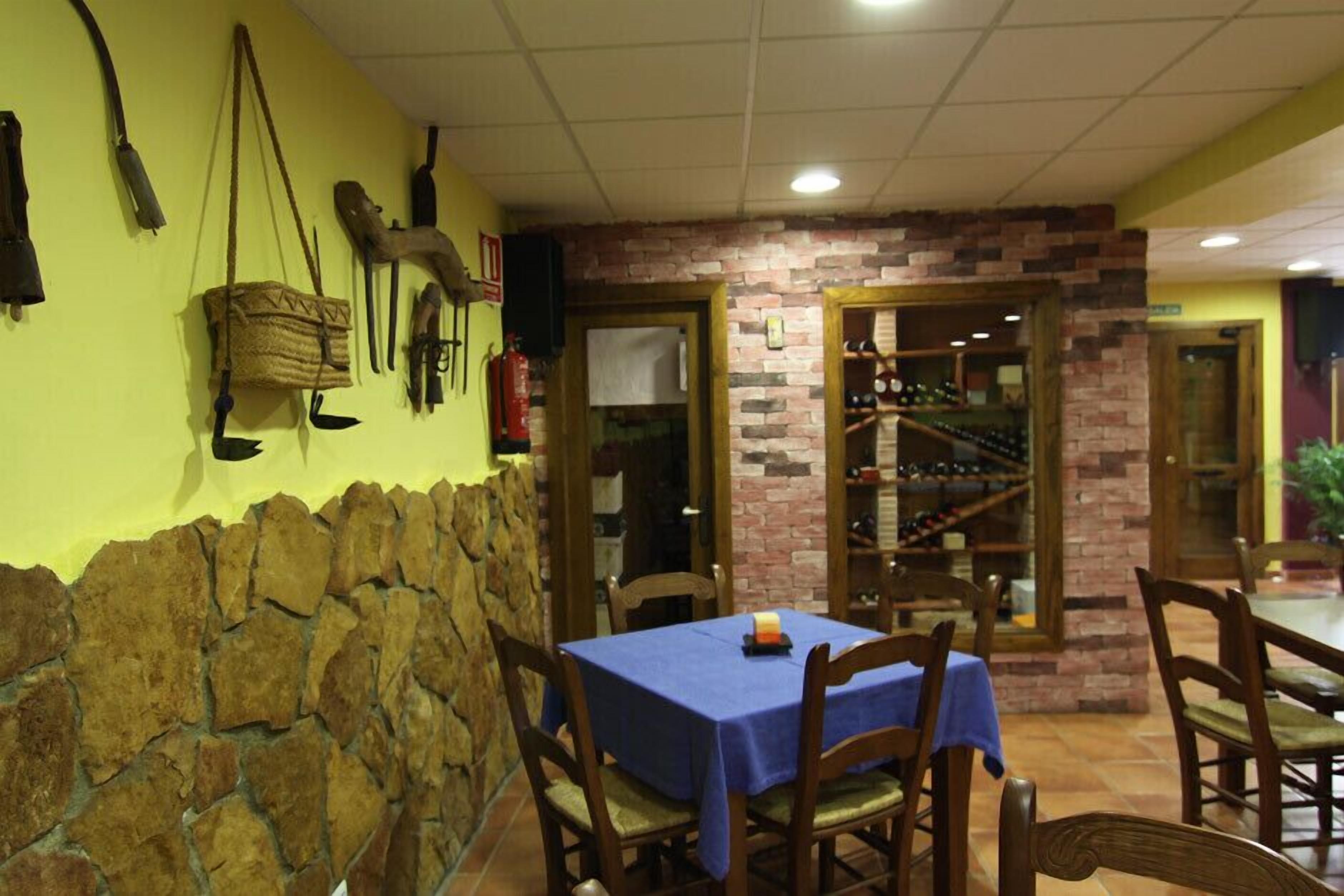 A restaurant with stone walls, wooden chairs, and a blue tablecloth.