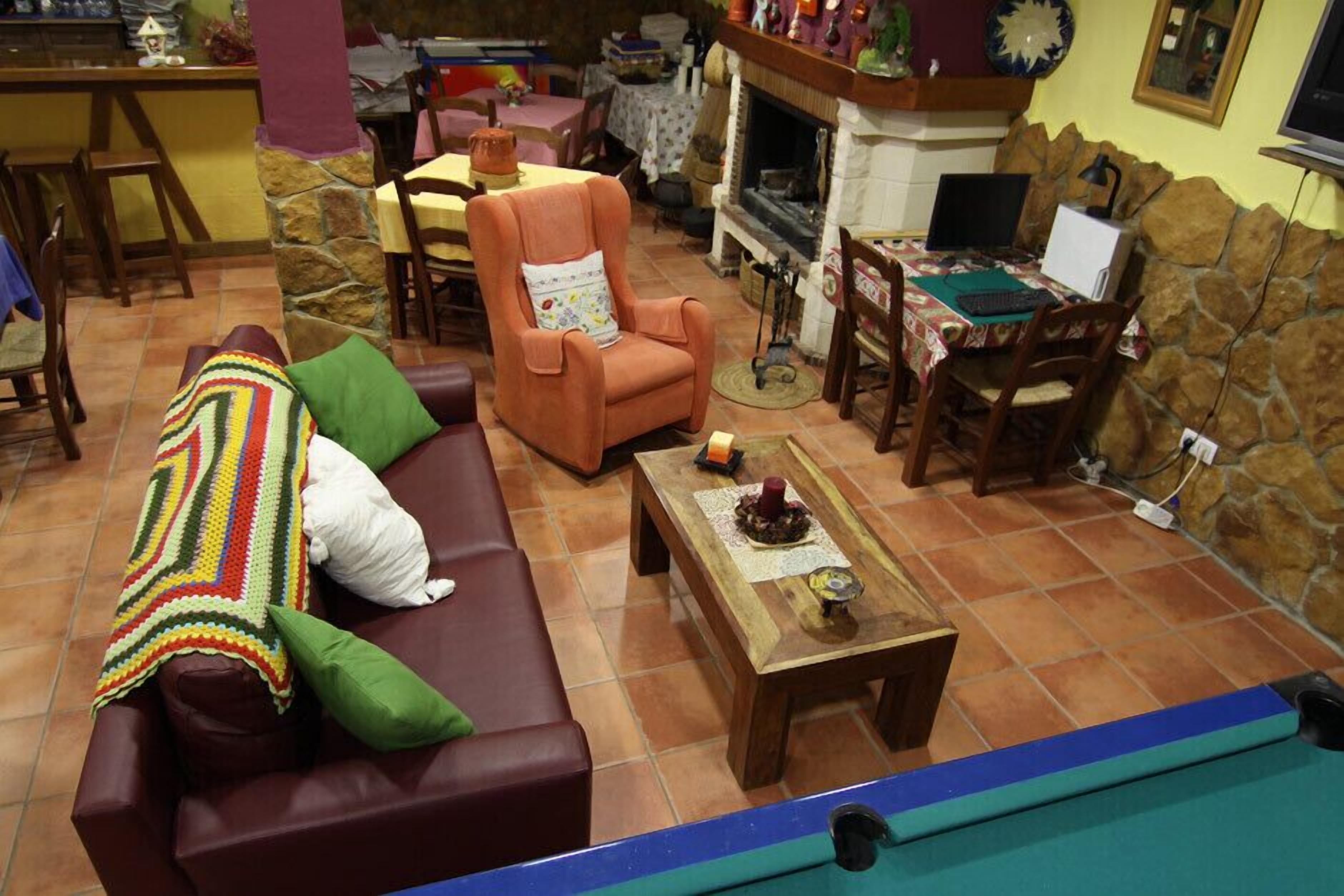 A cozy living room with a brown sofa, a colorful blanket, a wooden coffee table, and a fireplace.