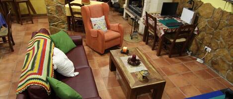 A cozy living room with a brown sofa, a colorful blanket, a wooden coffee table, and a fireplace.