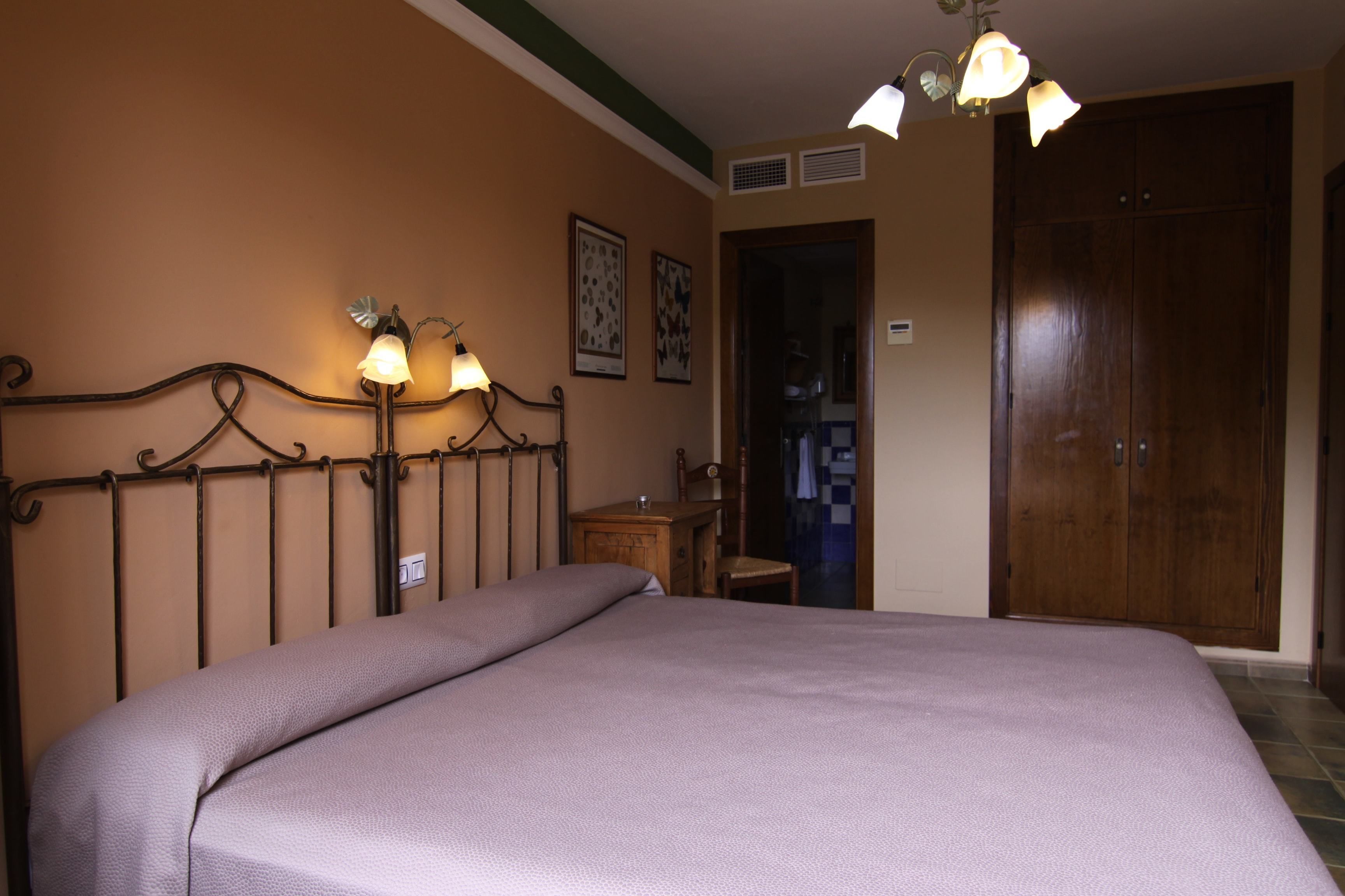 Un dormitorio con cama, mesita de noche, lámpara y armario.