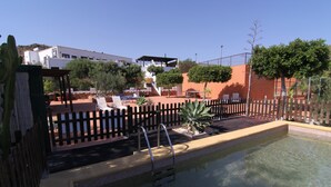 A pool area with a wooden fence, lounge chairs, and a small garden. - Los Palmitos Hospedería Rural (Nijar)