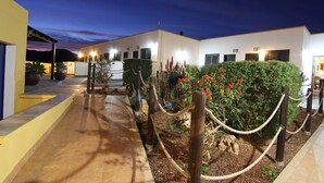 A modern building with a paved walkway and potted plants. - Los Palmitos Hospedería Rural (Nijar)