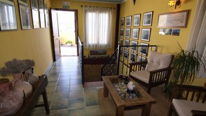 A cozy room with a wooden bench, a coffee table, and a sofa. There are framed pictures on the wall and a potted plant. - Los Palmitos Hospedería Rural (Nijar)