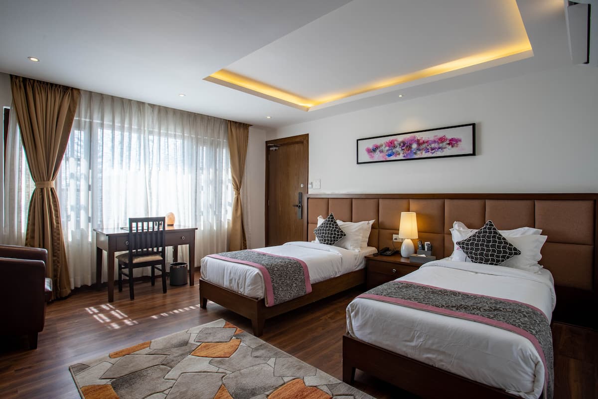 Quarto de hotel com duas camas, uma mesa e uma cadeira.
