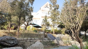 A garden with a stone pathway, large rocks, and trees. - Meraki Wellness Retreat (Burhanilkantha)
