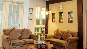 A spacious living room with two sofas, a coffee table, and a decorative clock on the wall. - Meraki Wellness Retreat (Burhanilkantha)