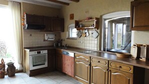 A kitchen with wooden cabinets, a dishwasher, and a window. - Ostsee Ferienhaus Welzin - Altes Schäferhaus (Damshagen)