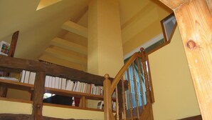 A wooden staircase with a wooden railing, a bookshelf with books, and a framed picture on the wall. - Ostsee Ferienhaus Welzin - Altes Schäferhaus (Damshagen)