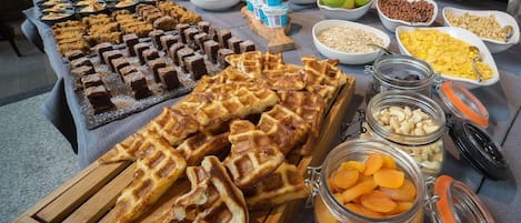 Una mesa de buffet con diversos alimentos, como waffles, frutas y nueces.